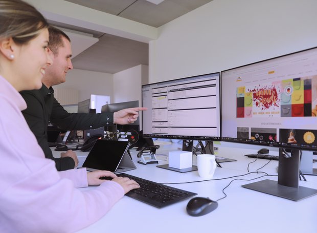 Ein Mitarbeiter von RBV Birkmann zeigt einer neuen Kollegin im Vertrieb ein Warenwirtschaftssystem am Computer.